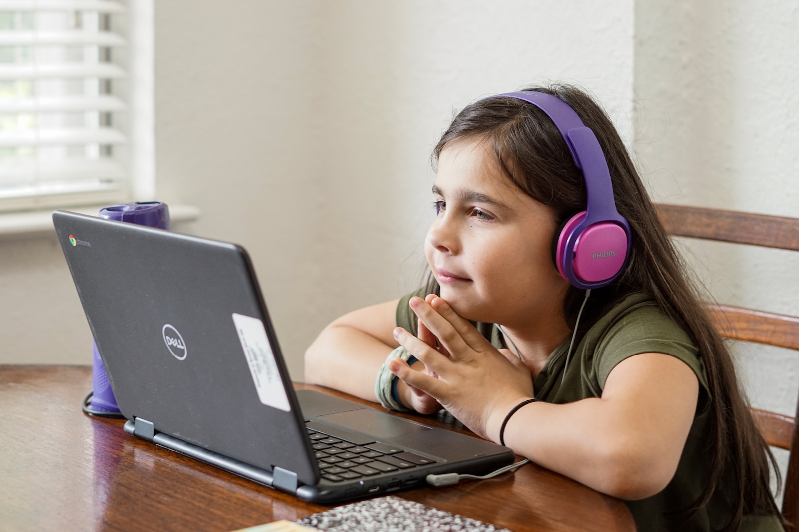 a little girl sitting at a table with a laptop